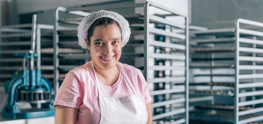 Young female adult with disability working in a kitchen and smiling