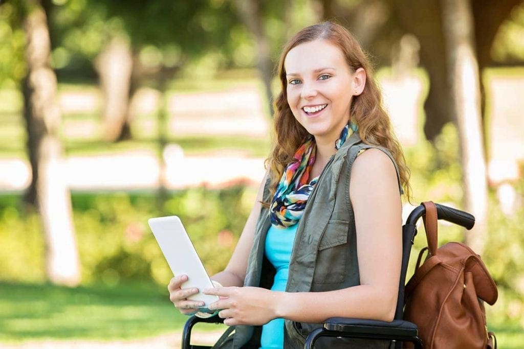 Young female student in wheelchair holding a tablet device