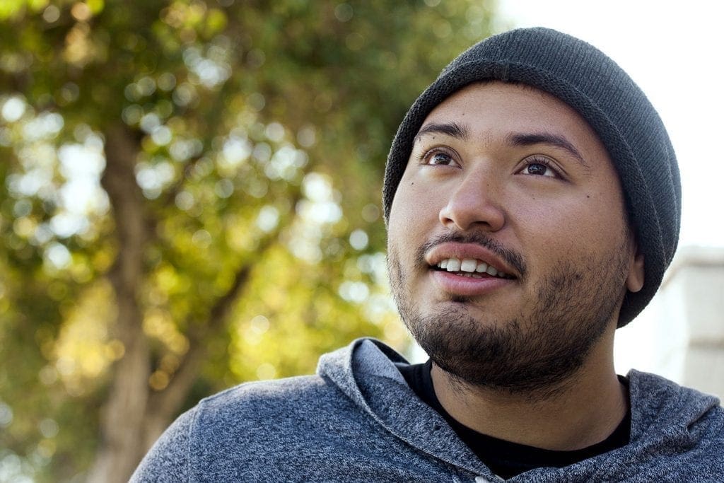 Young male adult wearing a beanie and a smile looking up